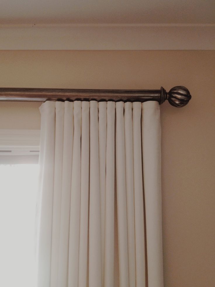 Ivory pinch-pleat curtains on a decorative rod