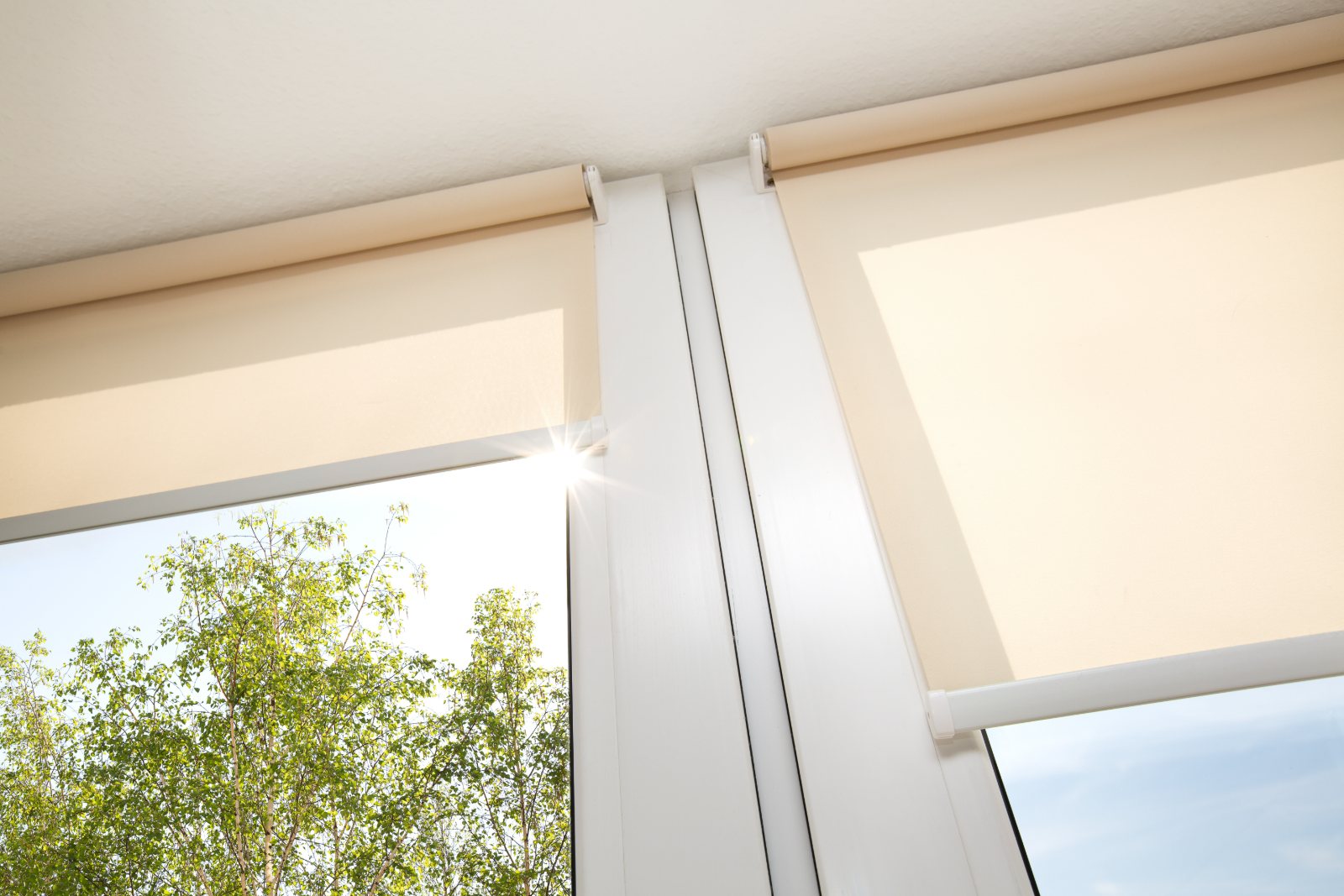 Natural linen roller blinds framing a coastal balcony with an ocean view
