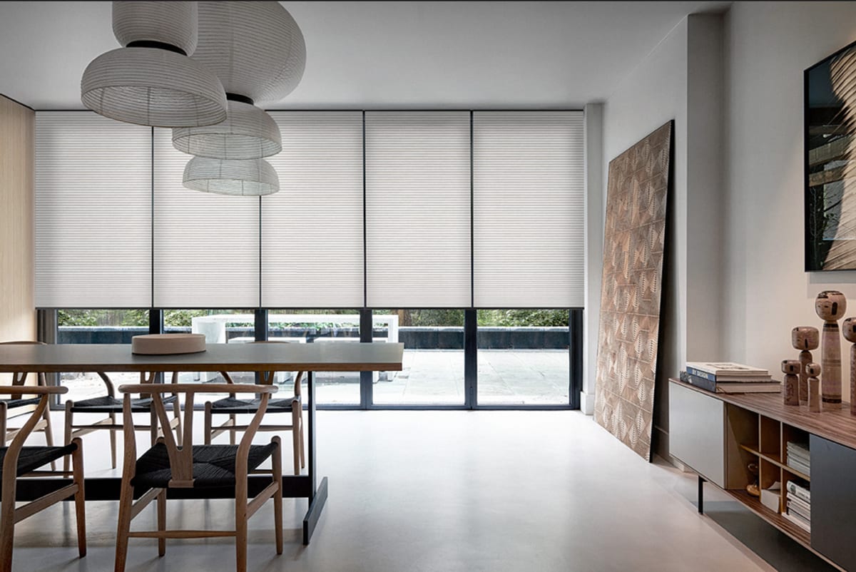 Cream honeycomb cellular blinds across floor-to-ceiling dining room windows